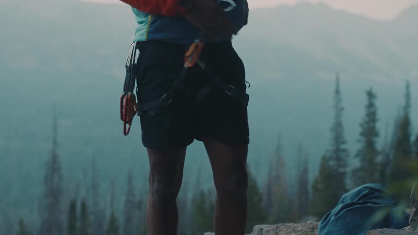 A man on a mountain attaches clips to his climbing belt