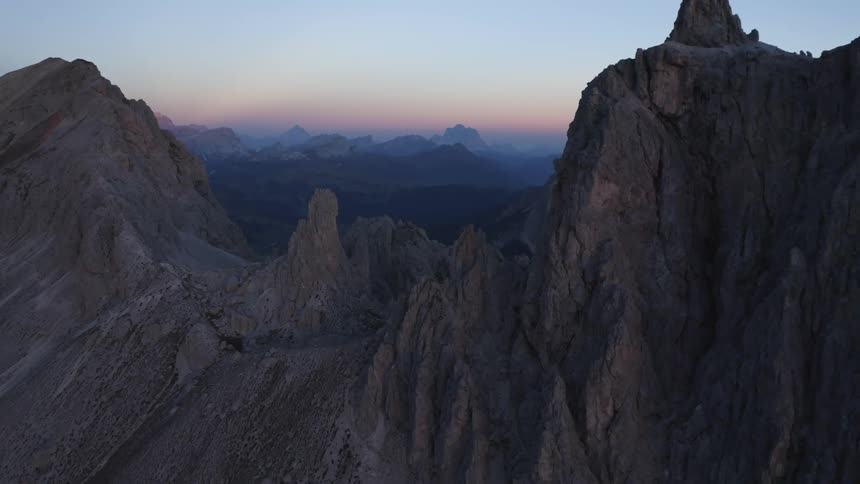 Red tinted horizon and mist covered mountainous terrain is visible through gap in mountain range