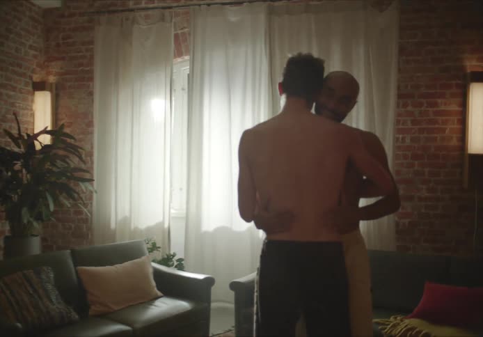Two men slow dance in middle of their living room