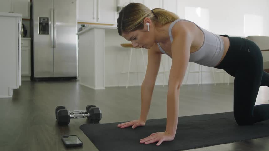 A woman is on the floor doing exercises on an exercise mat