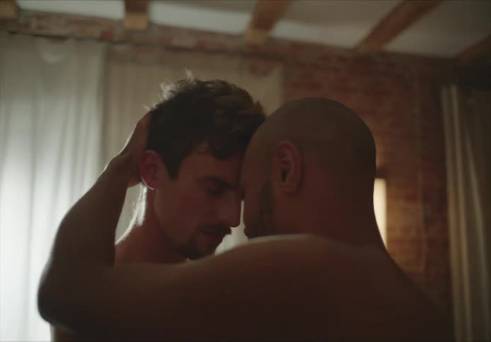 A shirtless male couple slow dancing in a living room
