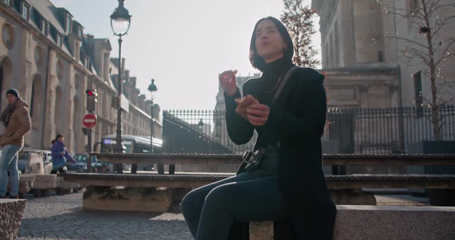A woman is spooked by a group of pigeons that fly by as she eats a muffin outdoors