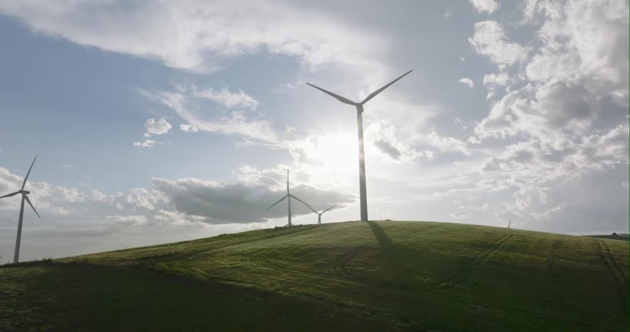 The windmills spin on the green hills