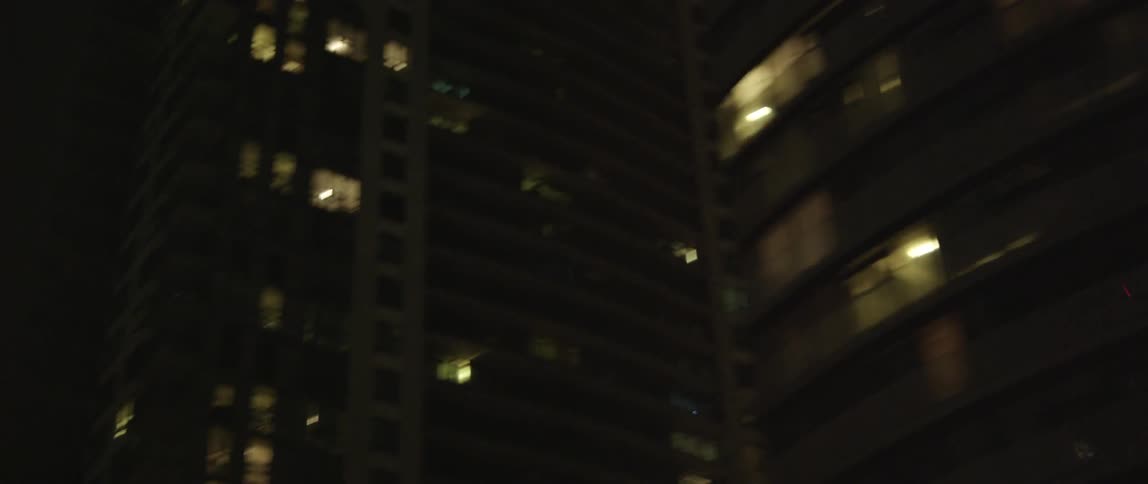 Moving past a city with lit buildings at night