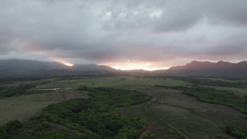 Aerial view of sunset on an overcast day over the fields close to the mountain