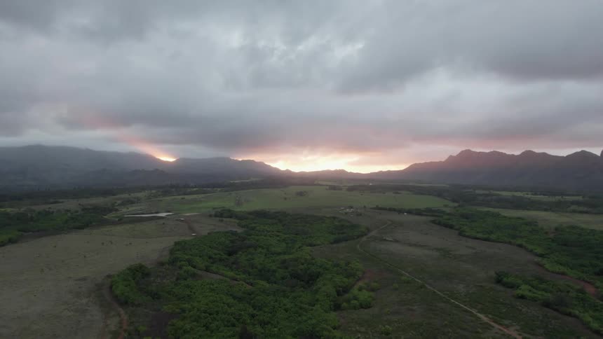Dense clouds cover the sky over a mountain range and field