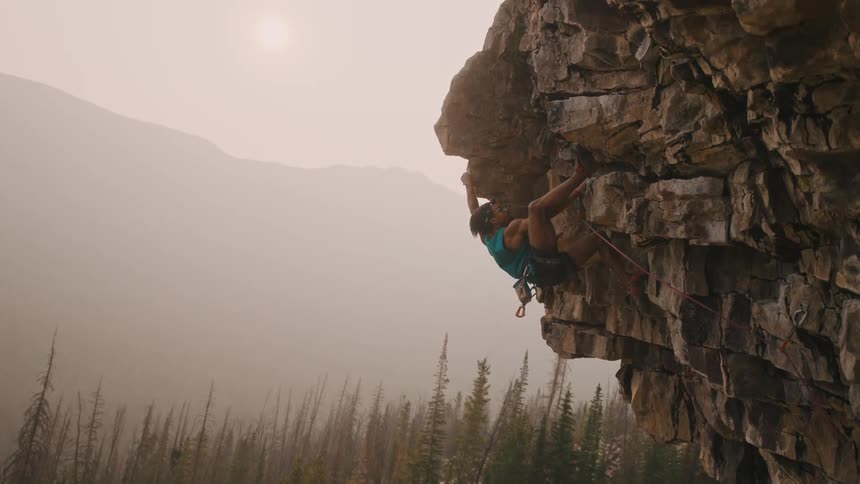 A rock climber makes his way up a protruding section of a mountain