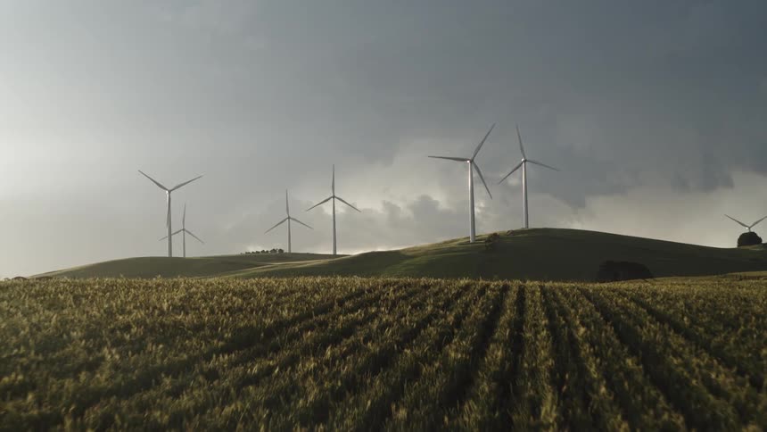 Aerial view of wind turbines spinning on a wind farm in the fields close to storm clouds