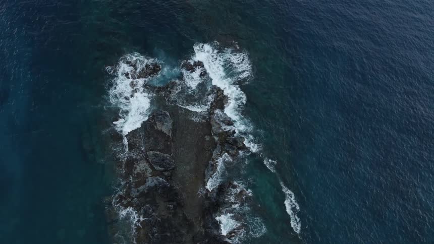 Aerial view ocean waves crashing on rocks