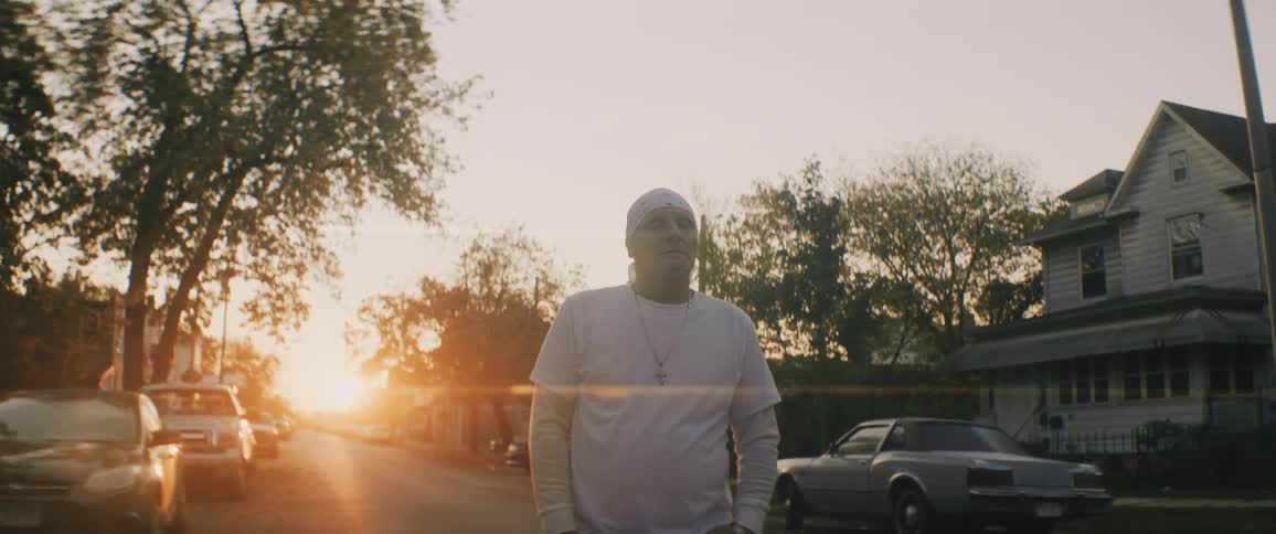 Man wearing white clothes walking down the street of a neighborhood at evening