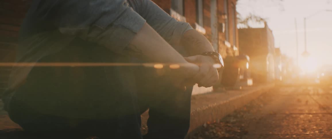 Close up of man sitting on a curb in middle of town in a small town