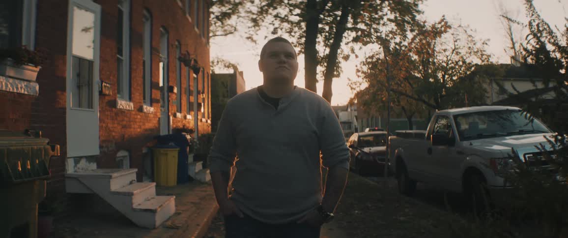 A teenage boy walks down a neighborhood sidewalk