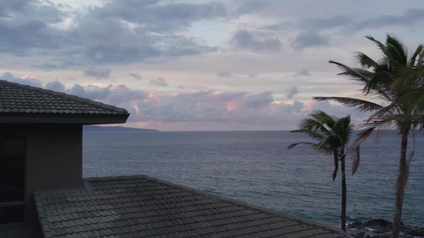Houses sit near shore as ocean stretches to red tinted horizon