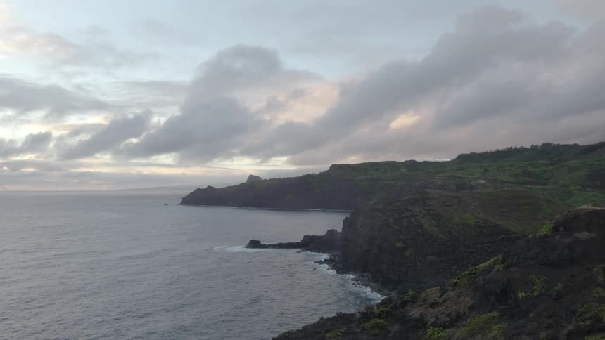 Waves roll in along the coast under a cloudy sky