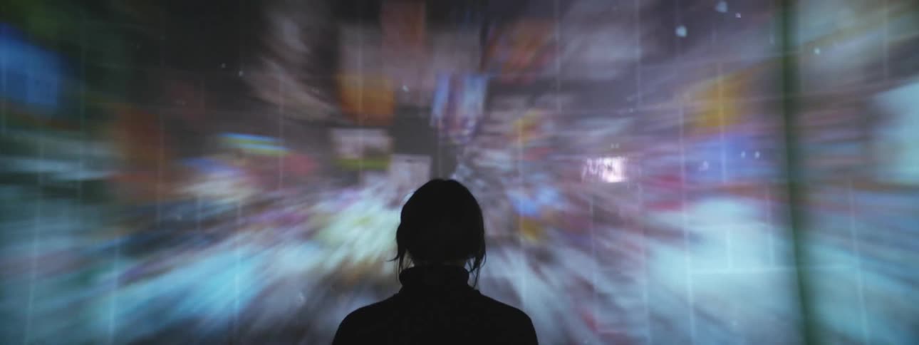 Silhouette of a persons head in front of a screen with fast moving colors and designs