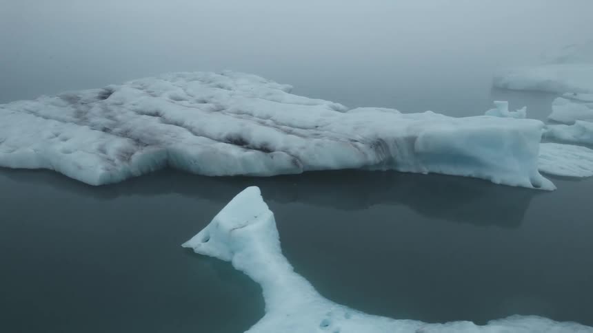 Large broken icebergs sit in still ocean water