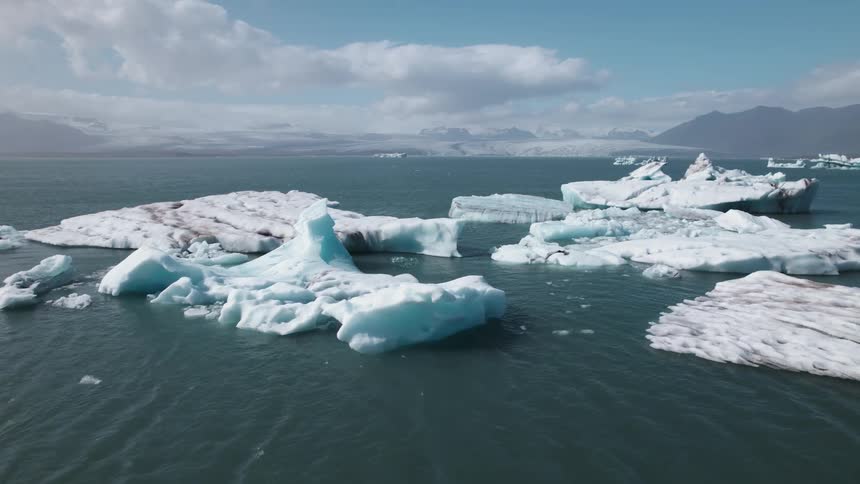 An aerial view of ice bergs floating out in the ocean