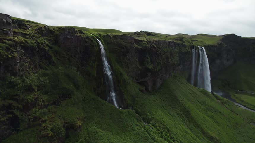 Waterfalls on the side of green mountain lands