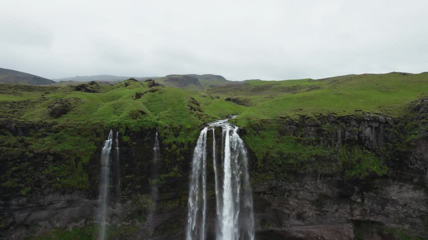 A river winds through green covered terrain to a waterfall flowing into a basin