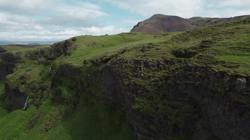 Aerial view of waterfalls flowing from the cliffs covered in green vegetation