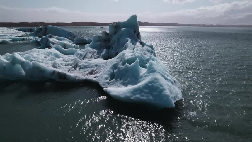 A small iceberg floating off the coast during the day