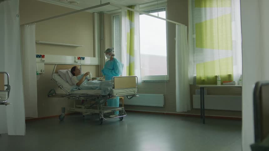Famale nurse with protective clothes attends to patient in clinic