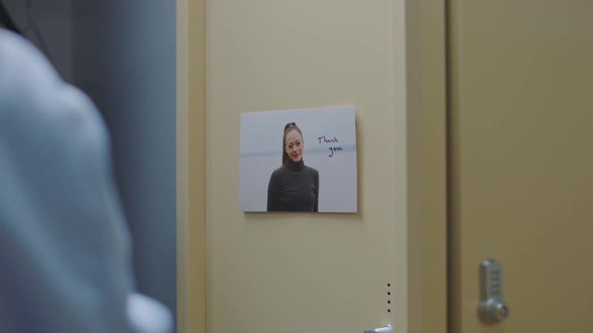 Female nurse with blue scrub opens locker lock door with a photograph and note saying thank you
