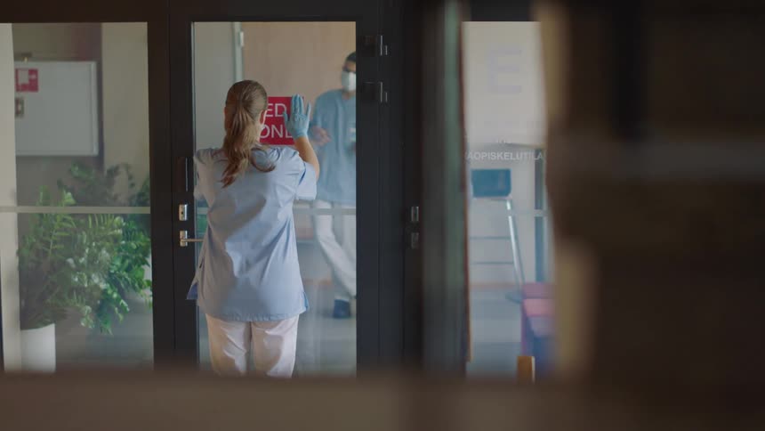 A woman places a red sign on the door