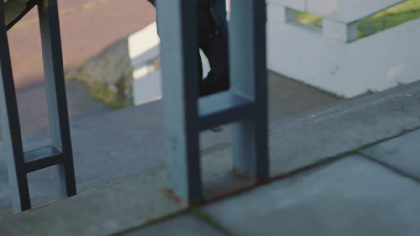 Female nurse with white shoes black pants and coat goes up clinic stairs