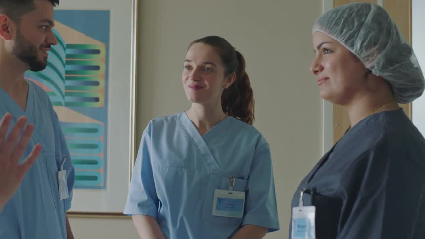 Three nurses in medical scrubs greeting each other at work