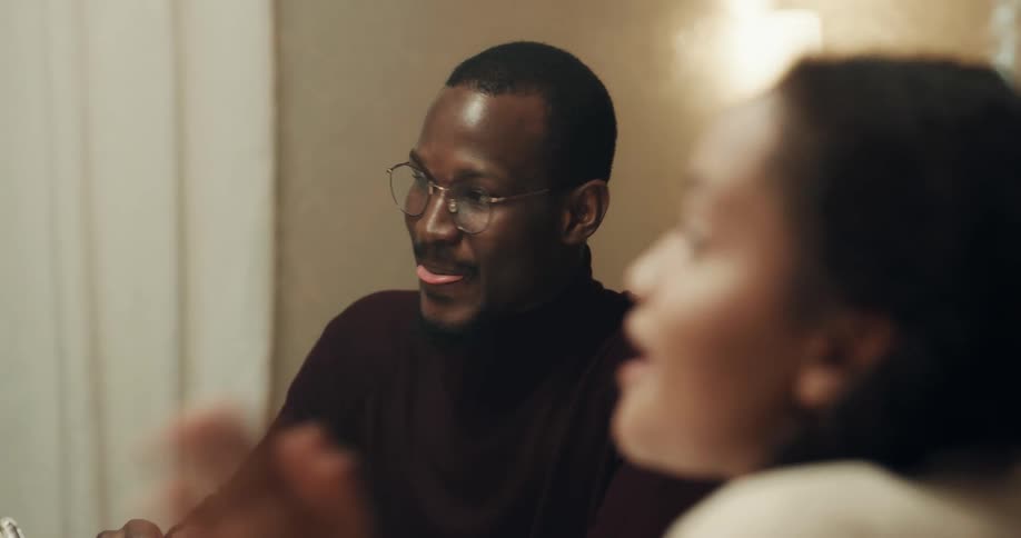 Family sits around table laughing and talking