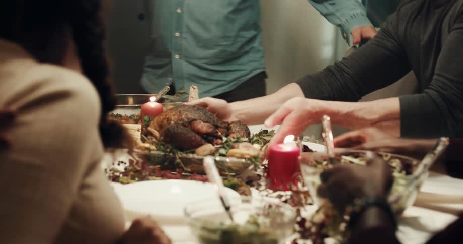 A woman presents a turkey dinner to a table of people celebrating