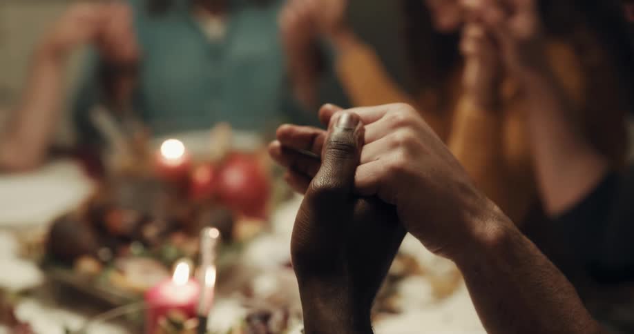 People holding hands around table