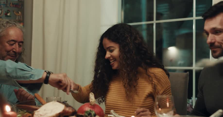 A group of friends laugh as they eat a turkey dinner at home