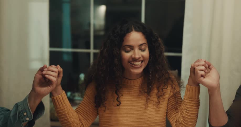 A young woman says grace while holding hands with her friends and family around a dining table