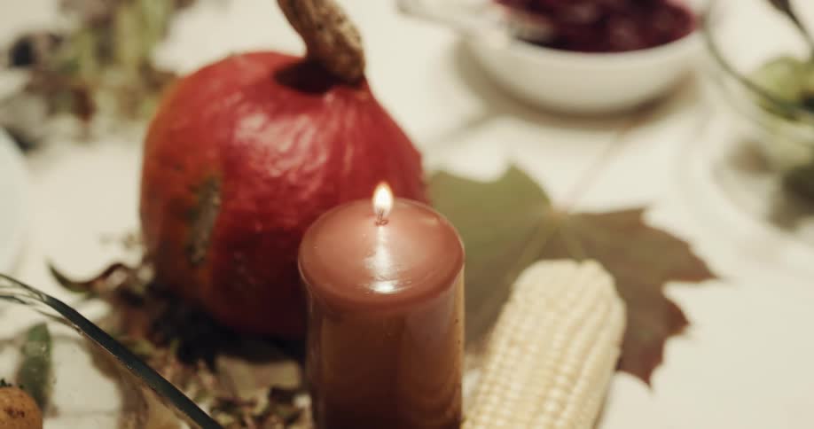 Hand lighting a candle and revealing a side dish at dinner table
