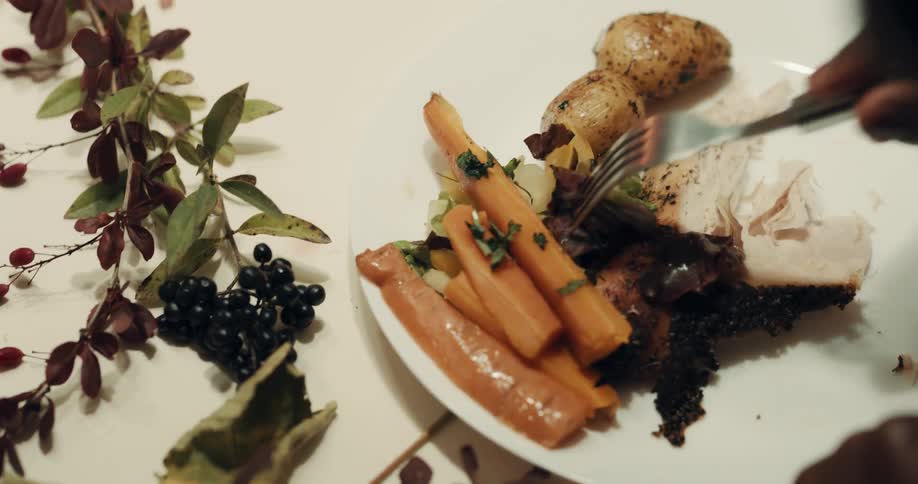 A person eats food from a plate at a table