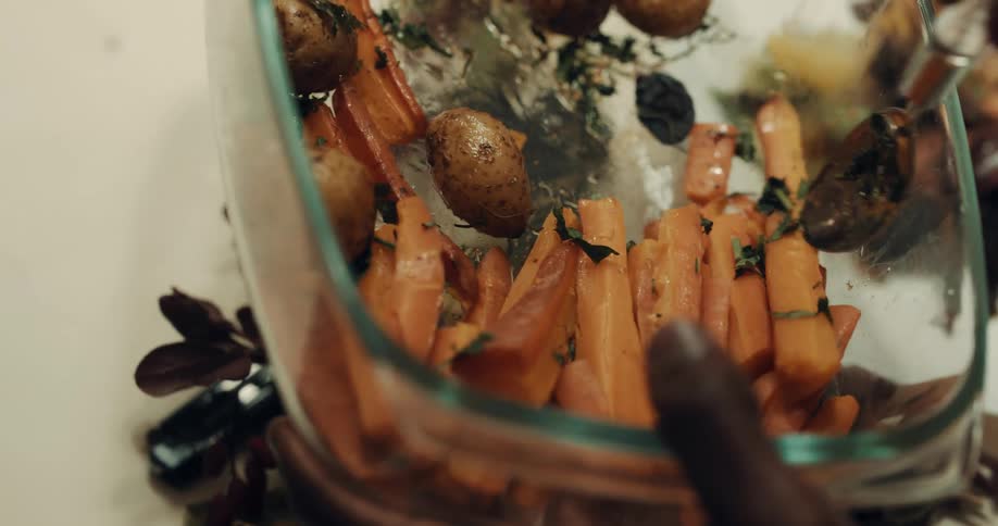 A man serves himself some carrots from a passed bowl before handing it back
