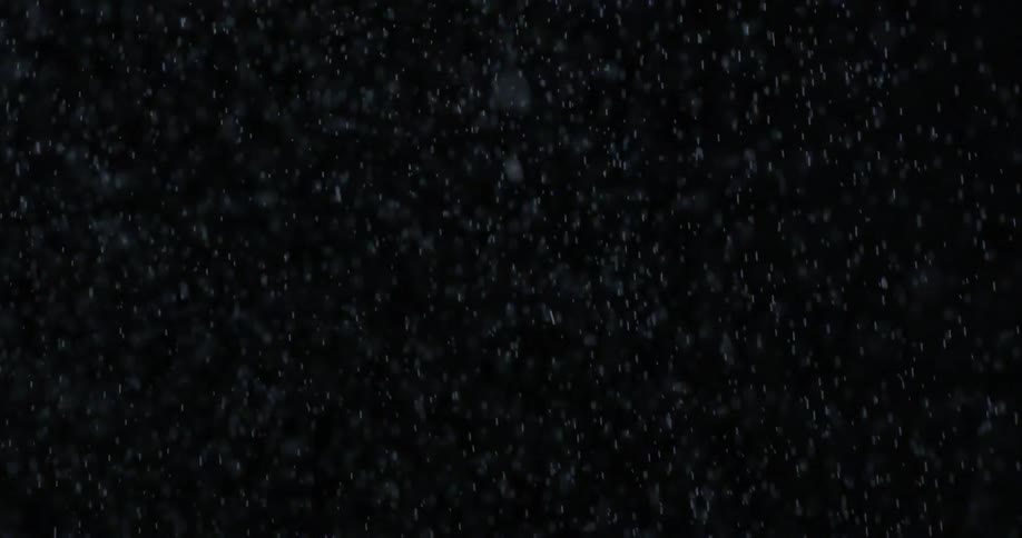 Snow slowly falls in a black area
