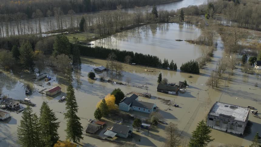 Flooded homes sit along the muddy waters of a rain swollen river