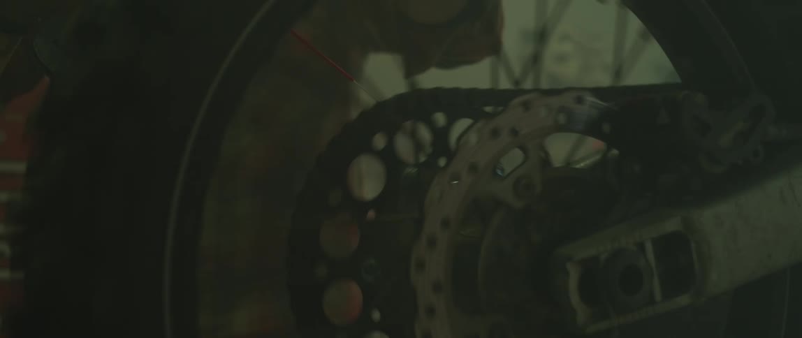 A man spins his bicycle wheel while pouring oil onto the chain
