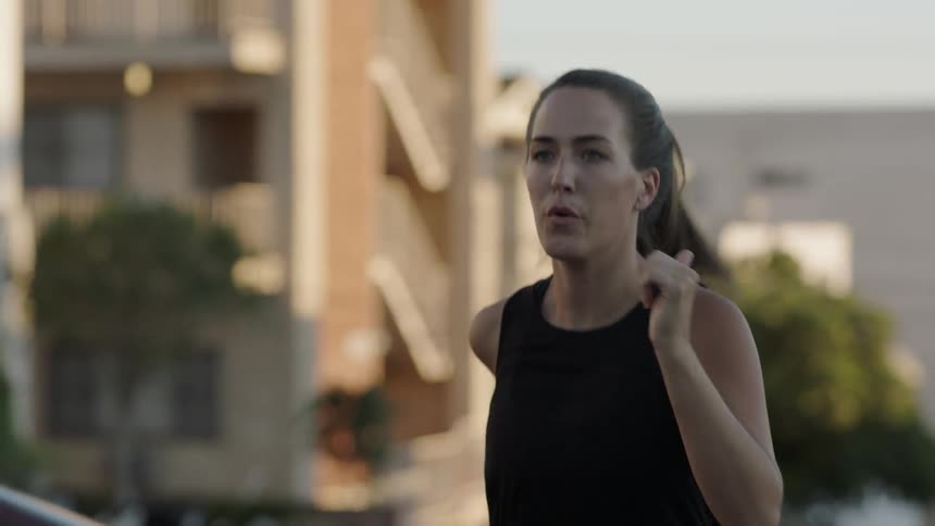 A woman is running uphill on a street