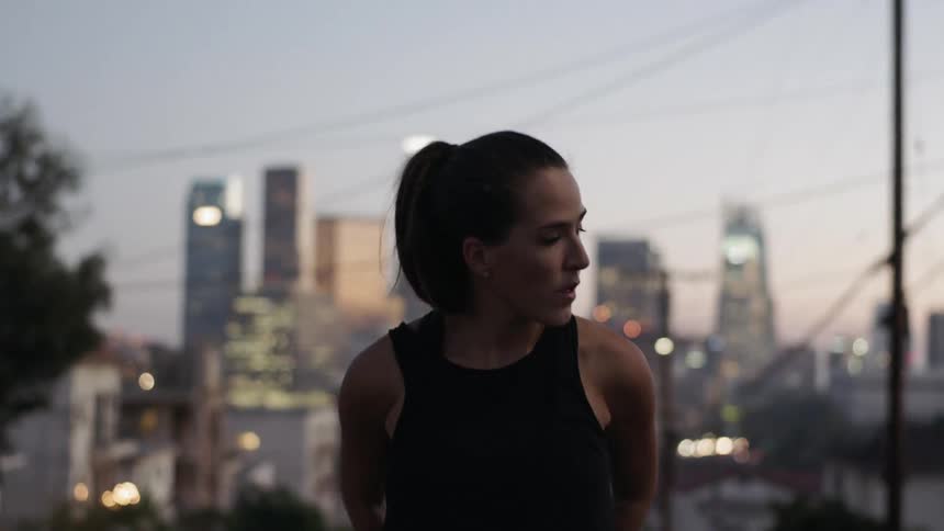 A woman stretches with a city in the background