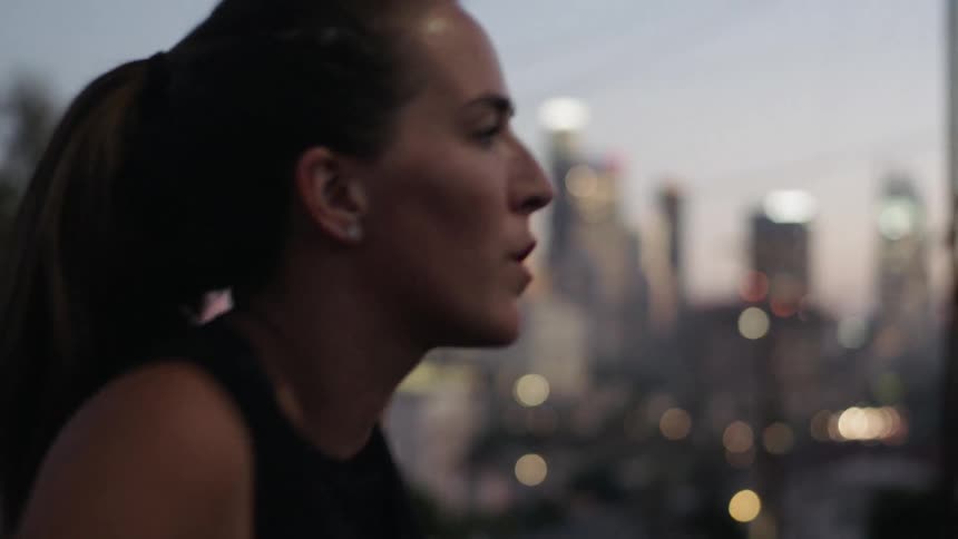 A woman is jumping up and down stretching in the street at sunset