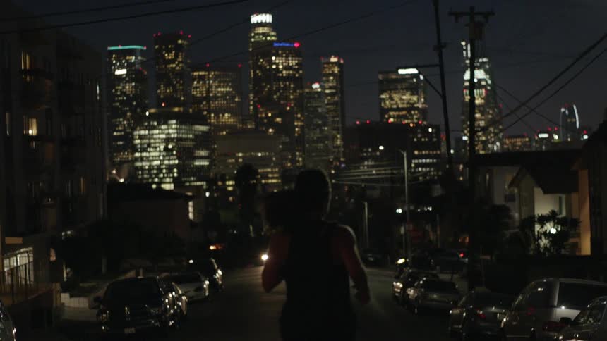 A woman jogs down a city street at night