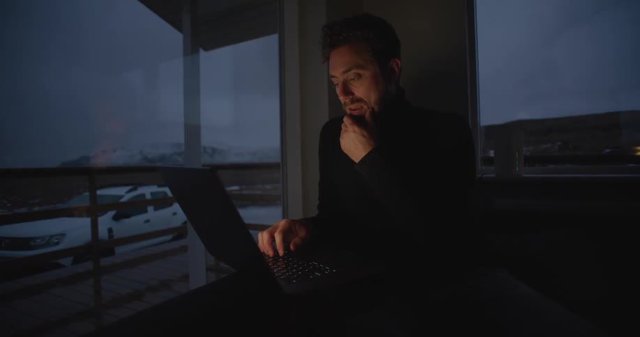 A man is thinking and typing on a laptop