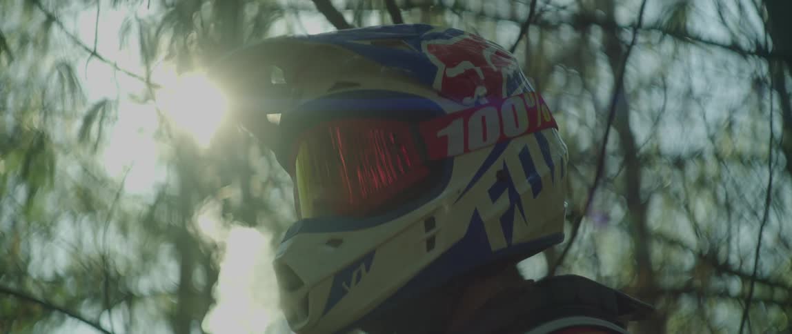 Man wearing a crash helmet lets a cloud of condensed breath out in the forest