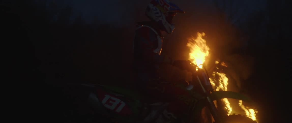 A motorcycle stops in front of a bonfire burning in the darkness of night