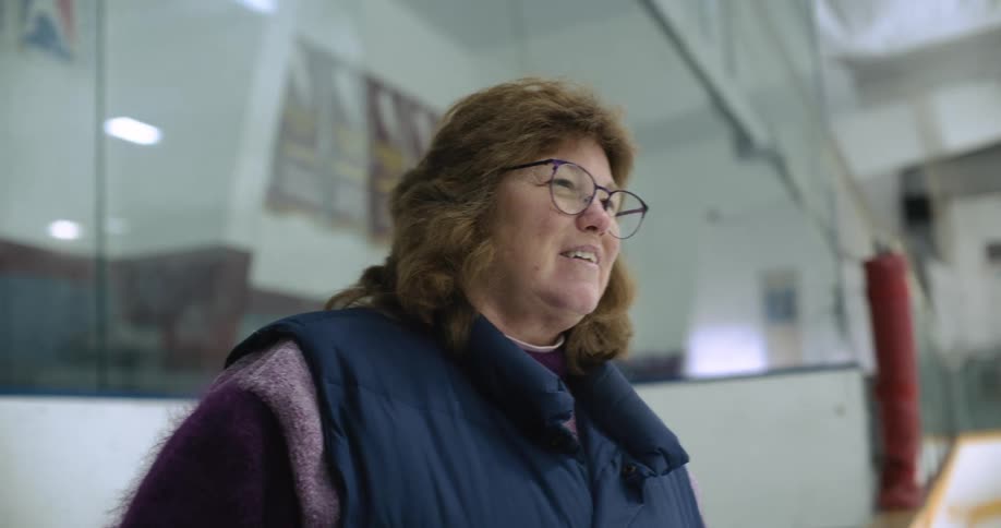 Mother proudly watches her daughter practice on a indoors ice hockey rink