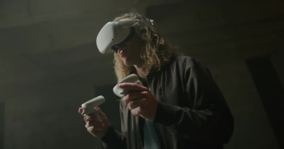 Blonde long haired man playing a virtual reality game in vacant room
